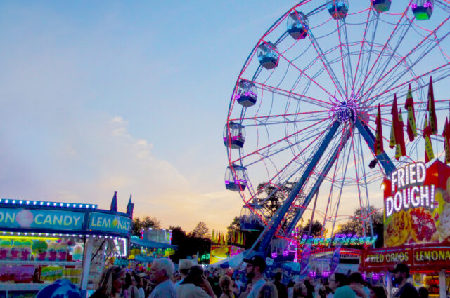 A low-angle photograph of a fair scene featuring a prominent carousel