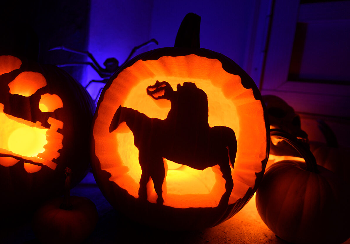 A jack-o-lantern with a headless horseman cut out of it.