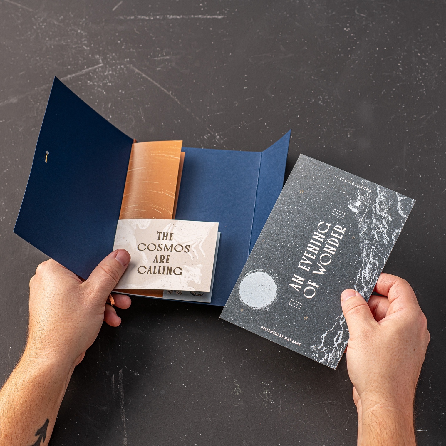 Photograph of hands opening the booklet containing the 2024 Monroe Community College Foundation Gold Star Gala invitation
