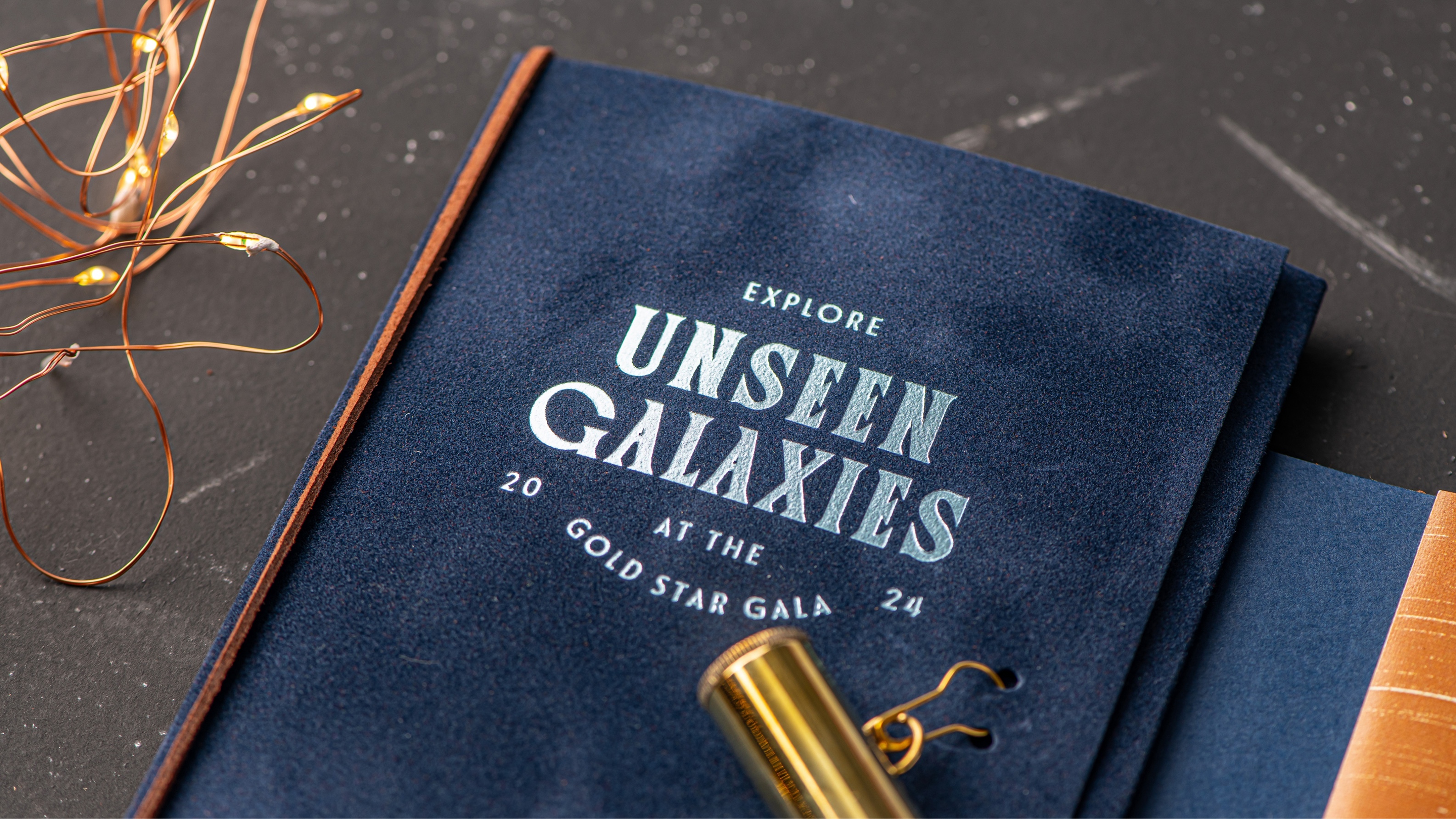 Detailed photograph of the cover of the booklet contained within the 2024 Monroe Community College Foundation Gold Star Gala invitation