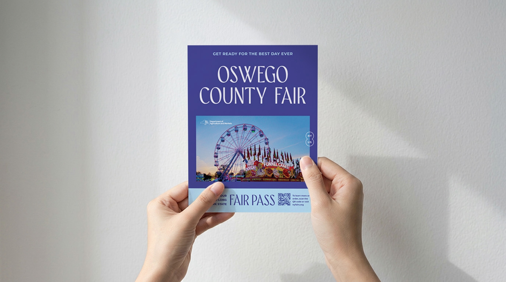 Hands holding the Fair Pass for the 2025 New York State County & Local Fairs